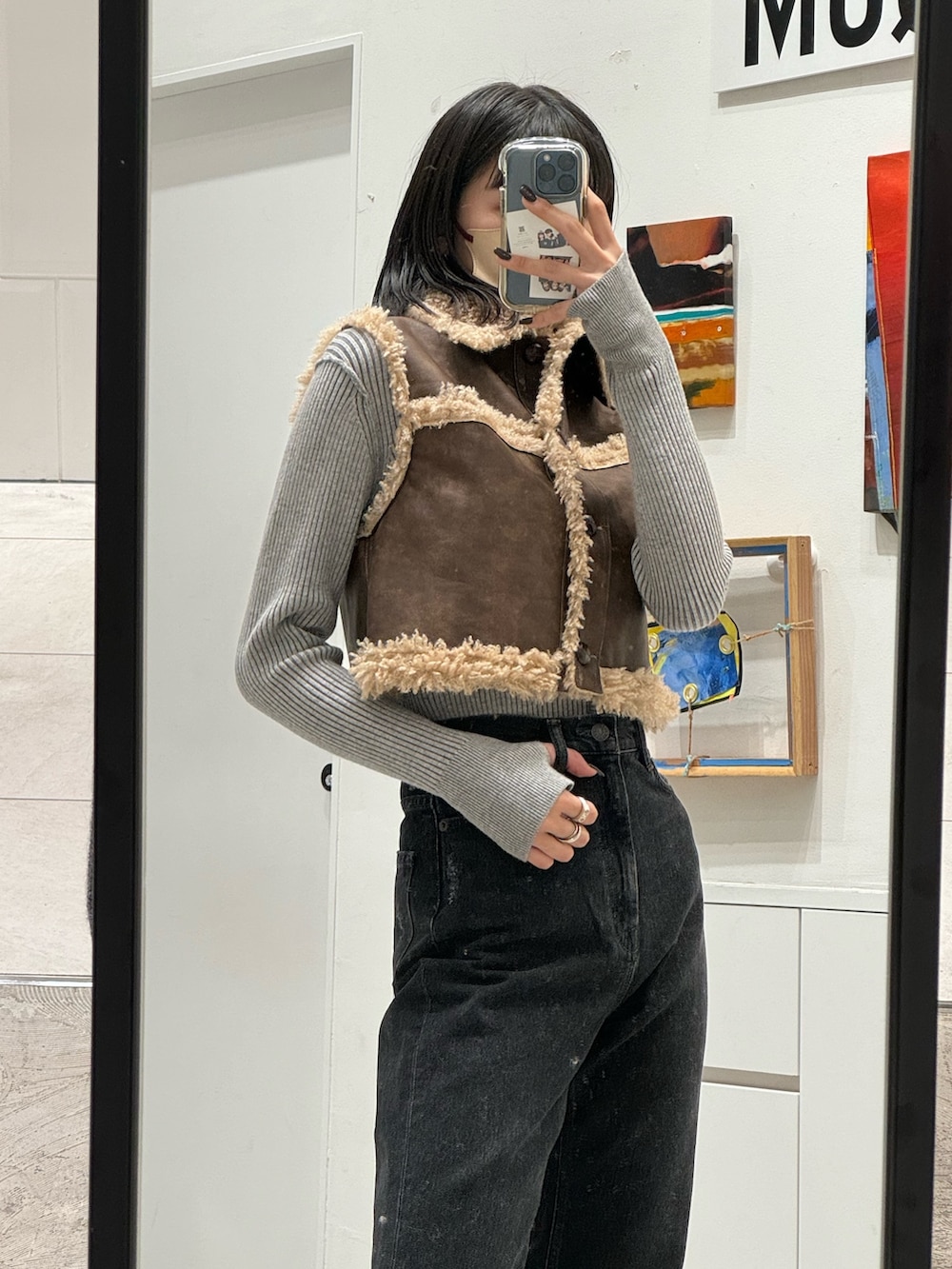 ブラック系のデニムパンツ、ブラウン系のベスト、グレー系のニット/セーターを着用したレディースの秋コーディネートの4枚目の写真