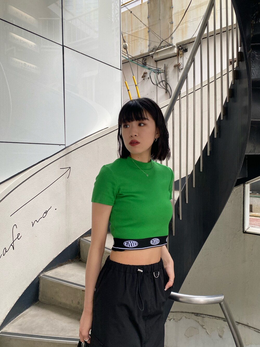 ブラック系のスカート、ブラック系のハンドバッグ、グリーン系のTシャツ/カットソーを着用したレディースの春コーディネートの6枚目の写真