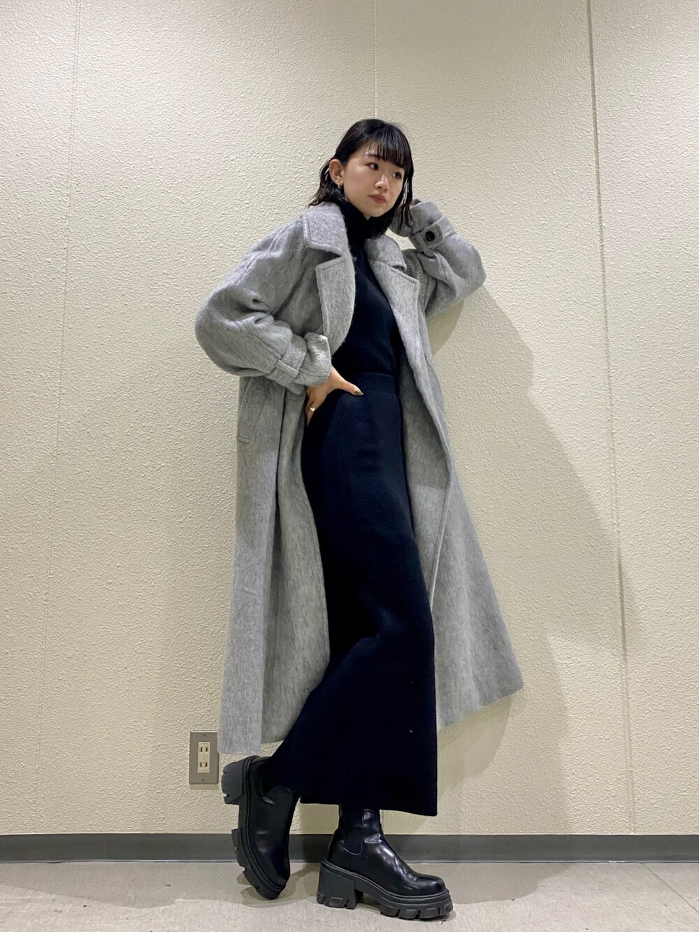 ブラック系のブーツ、グレー系のチェスターコート、ブラック系のスカートを着用したレディースの冬コーディネートの2枚目の写真