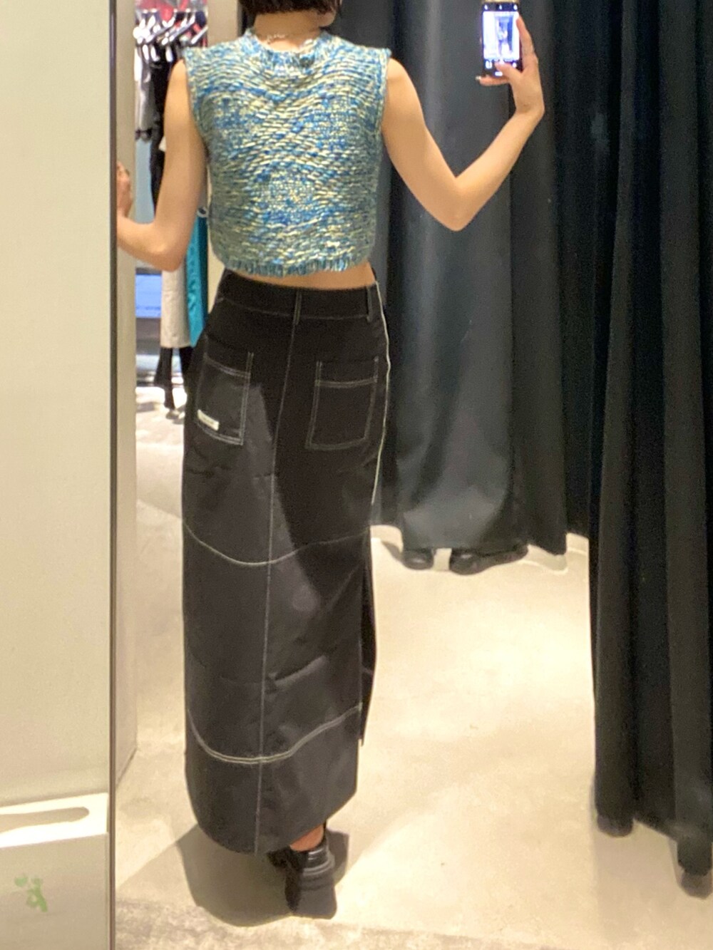 ブラック系のサンダル、ブラック系のスカート、ブルー系のベストを着用したレディースの夏コーディネートの4枚目の写真