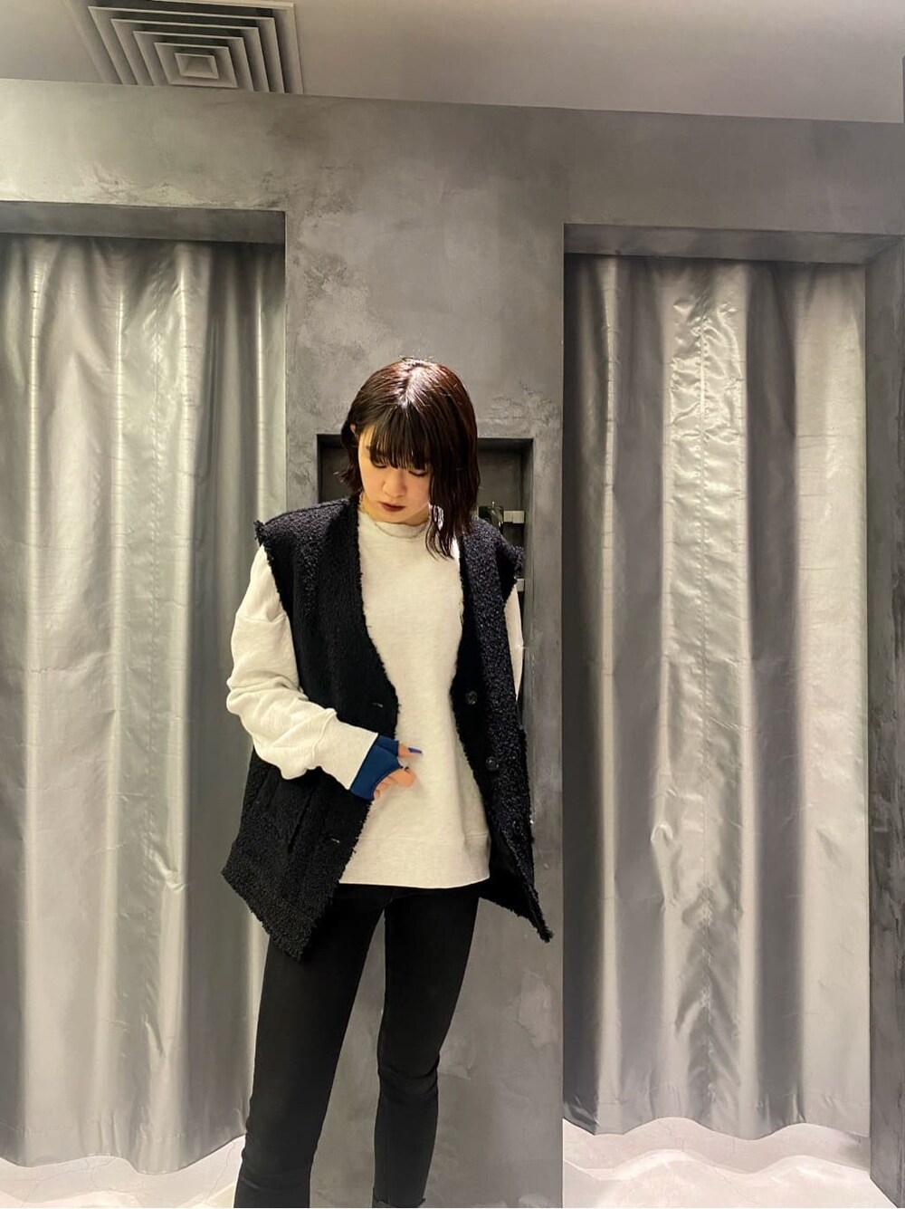 ブラック系のベスト、グレー系のスウェット、ブルー系のアームカバーを着用したレディースの秋コーディネートの4枚目の写真