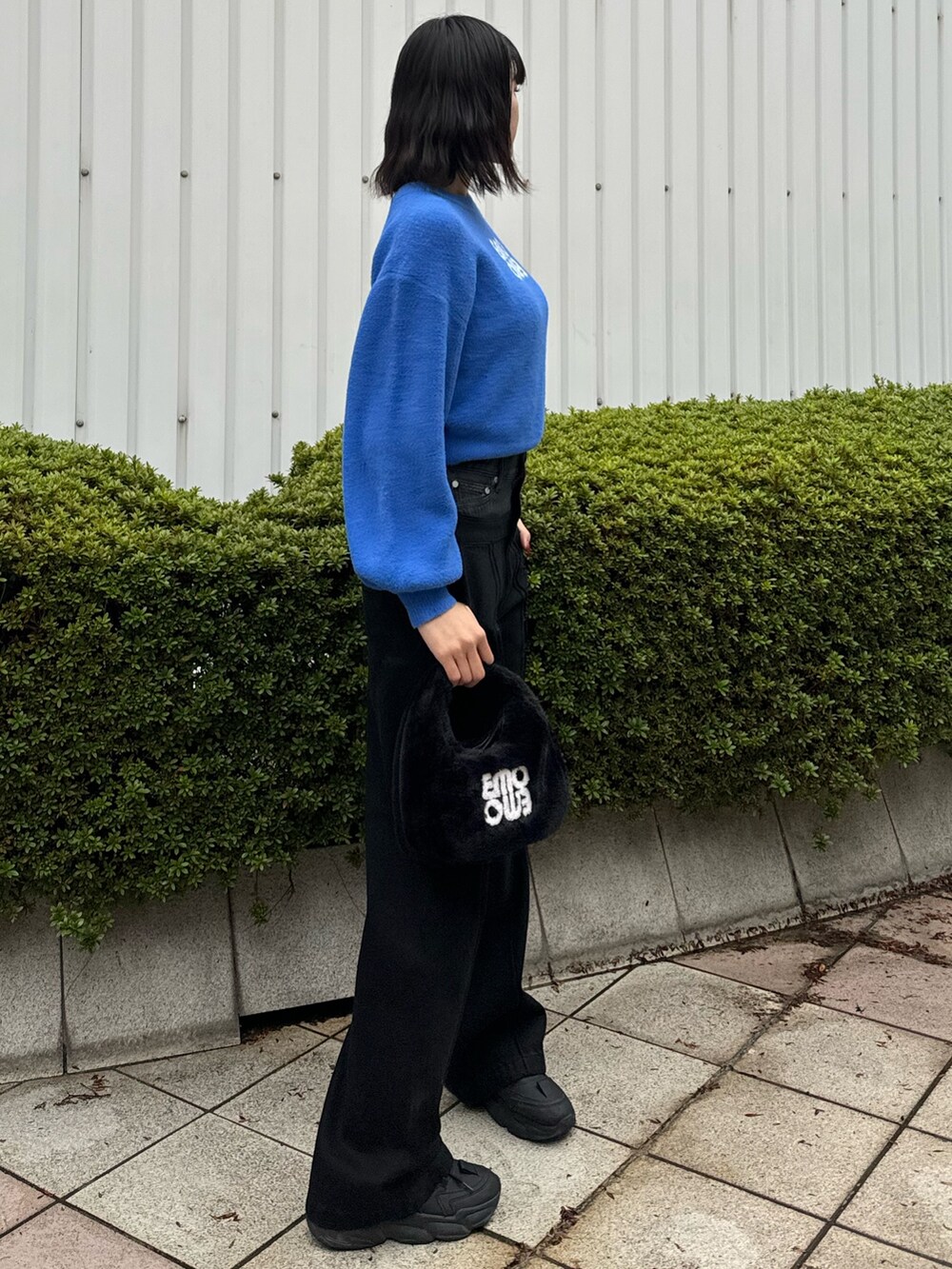 ブルー系のニット/セーター、ブラック系のデニムパンツ、ブラック系のハンドバッグを着用したレディースの冬コーディネートの3枚目の写真