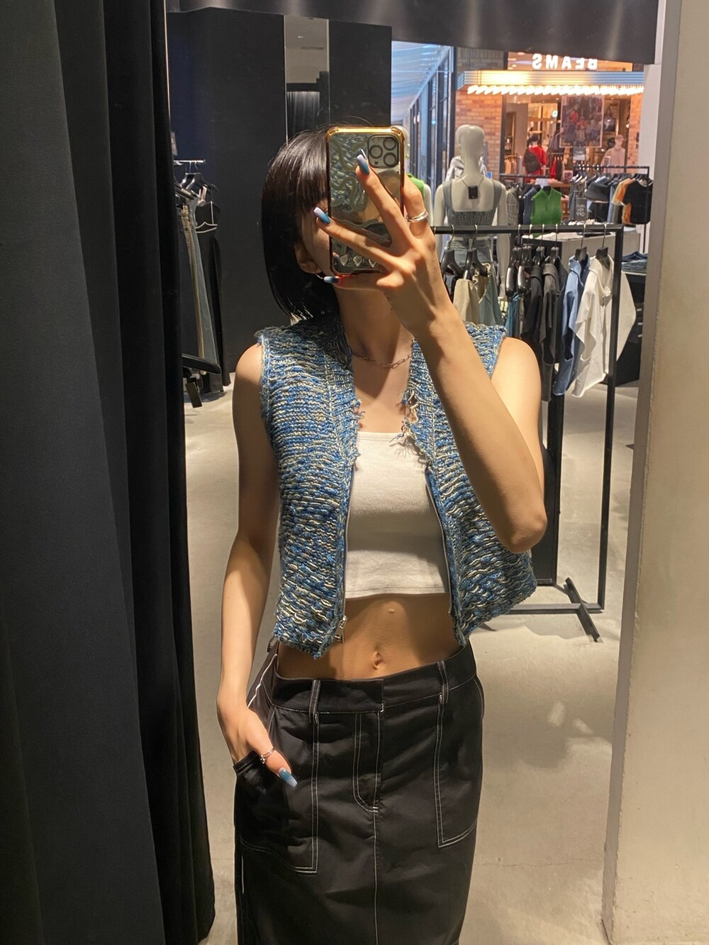 ブラック系のサンダル、ブラック系のスカート、ブルー系のベストを着用したレディースの夏コーディネートの5枚目の写真