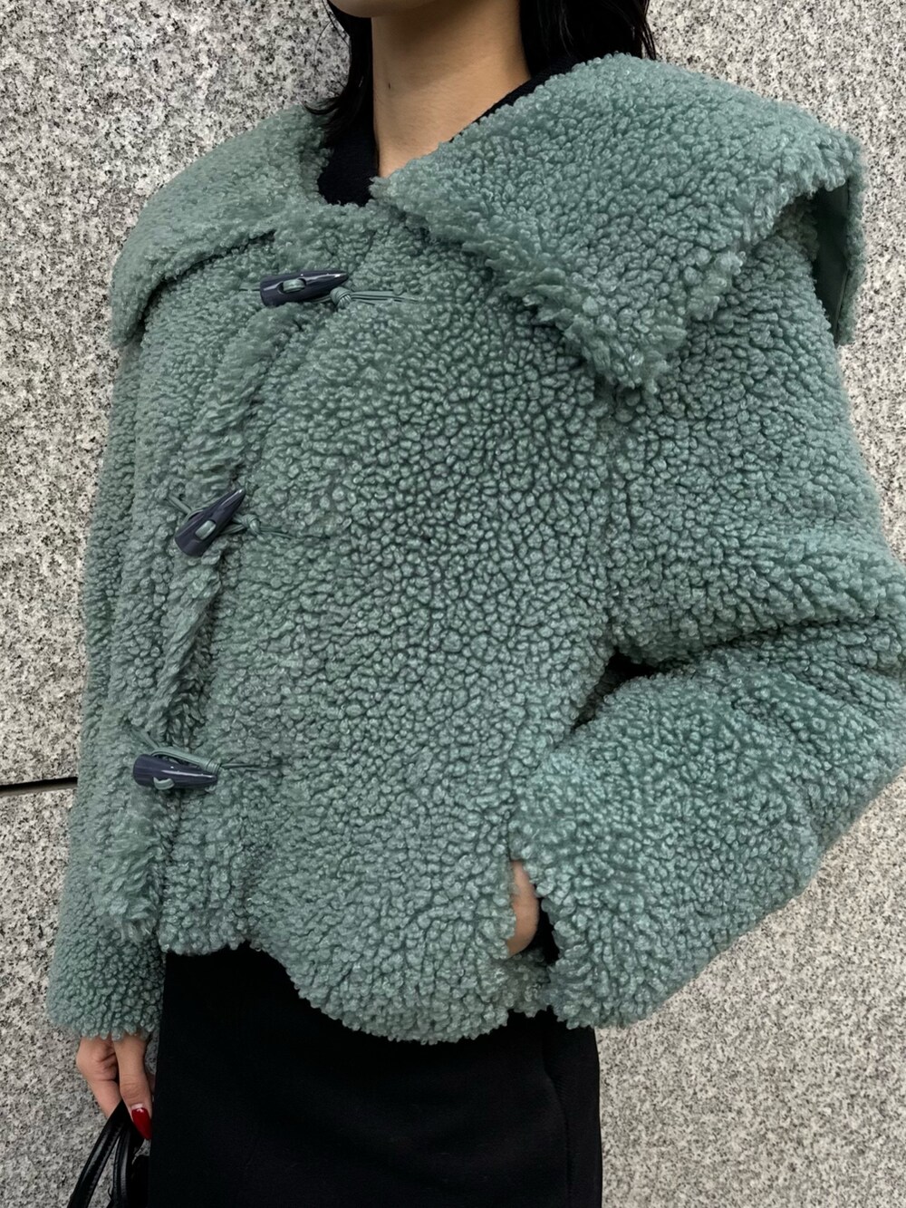 グリーン系のブルゾン、ブラック系のスカート、その他のブーツを着用したレディースの冬コーディネートの8枚目の写真