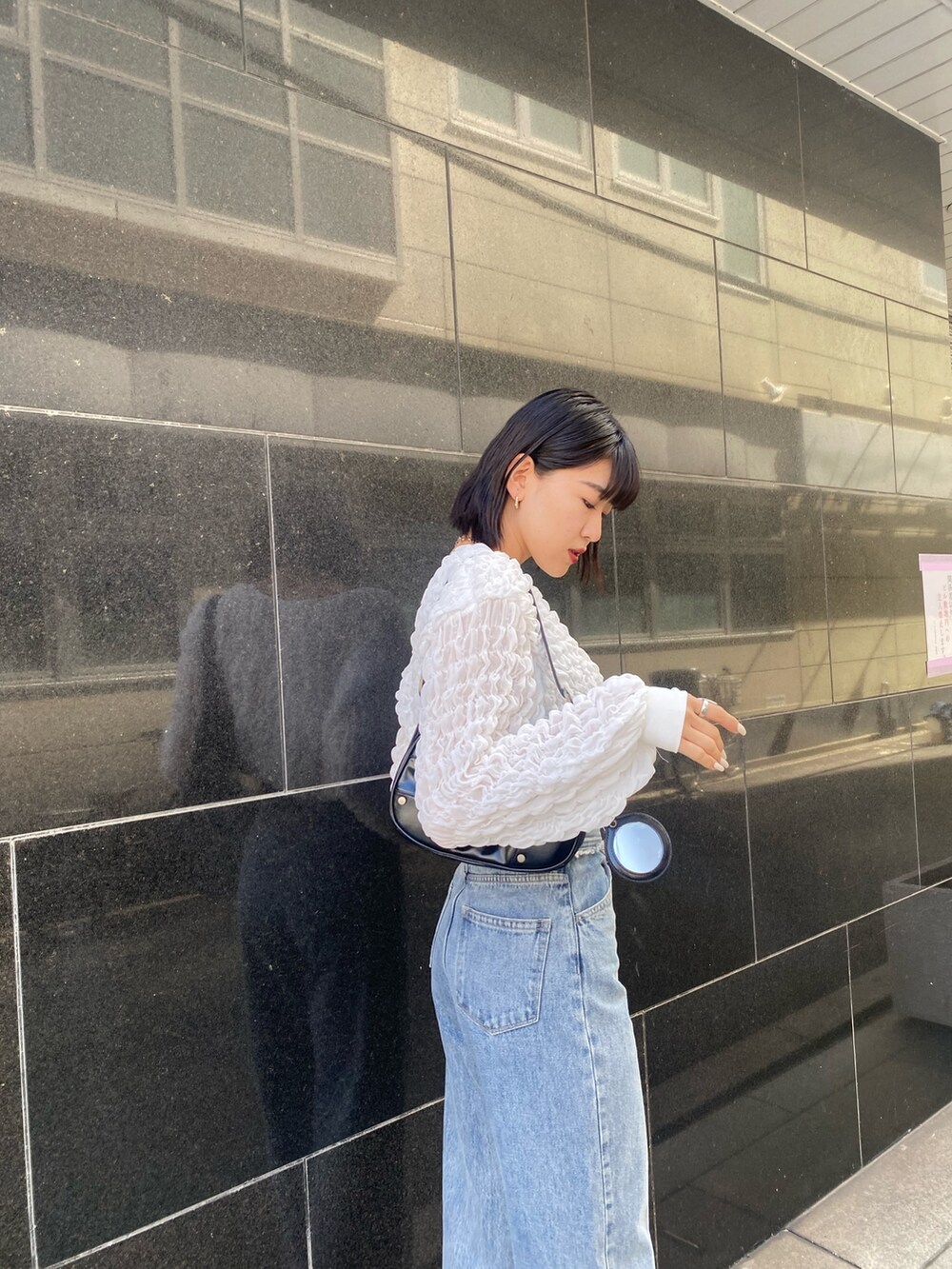 ブルー系のデニムパンツ、ブラック系のブーツ、ホワイト系のTシャツ/カットソーを着用したレディースの春コーディネートの6枚目の写真