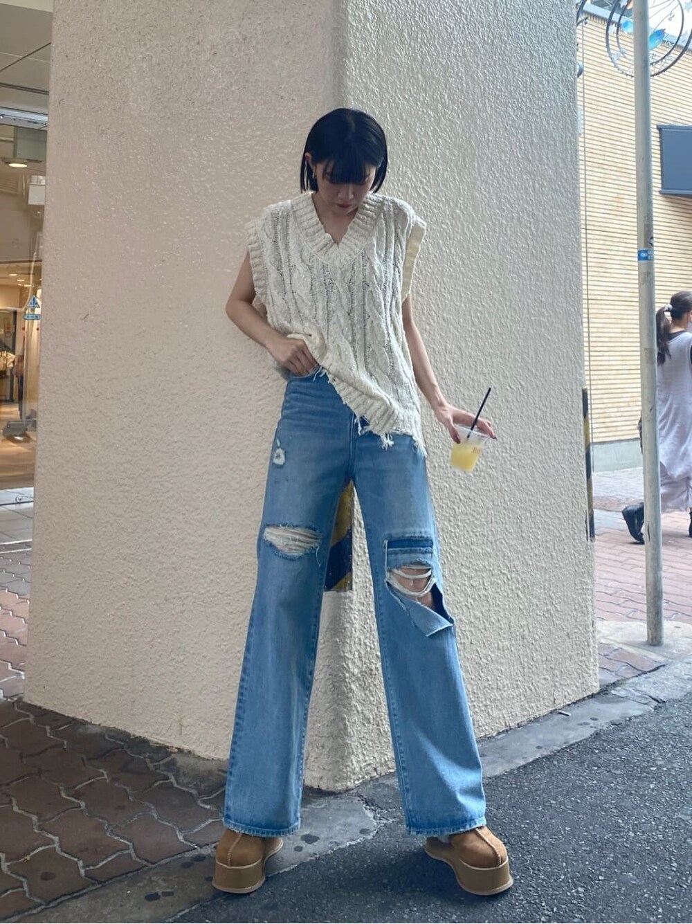 ブルー系のデニムパンツ、ベージュ系のスリッポン、ホワイト系のベストを着用したレディースの夏コーディネートの2枚目の写真