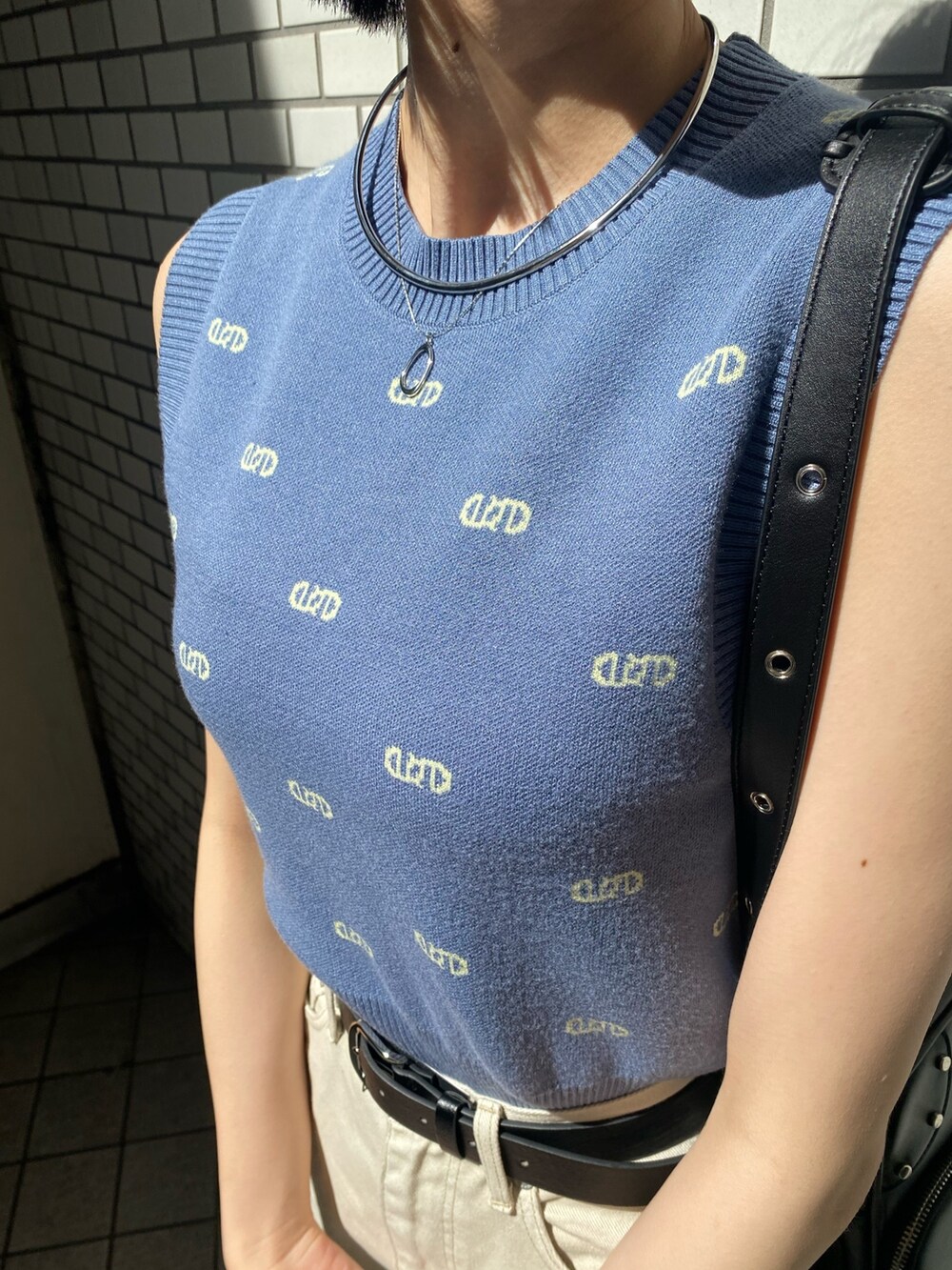 ブラック系のショルダーバッグ、ホワイト系のサンダル、ホワイト系のデニムパンツを着用したレディースの春コーディネートの8枚目の写真