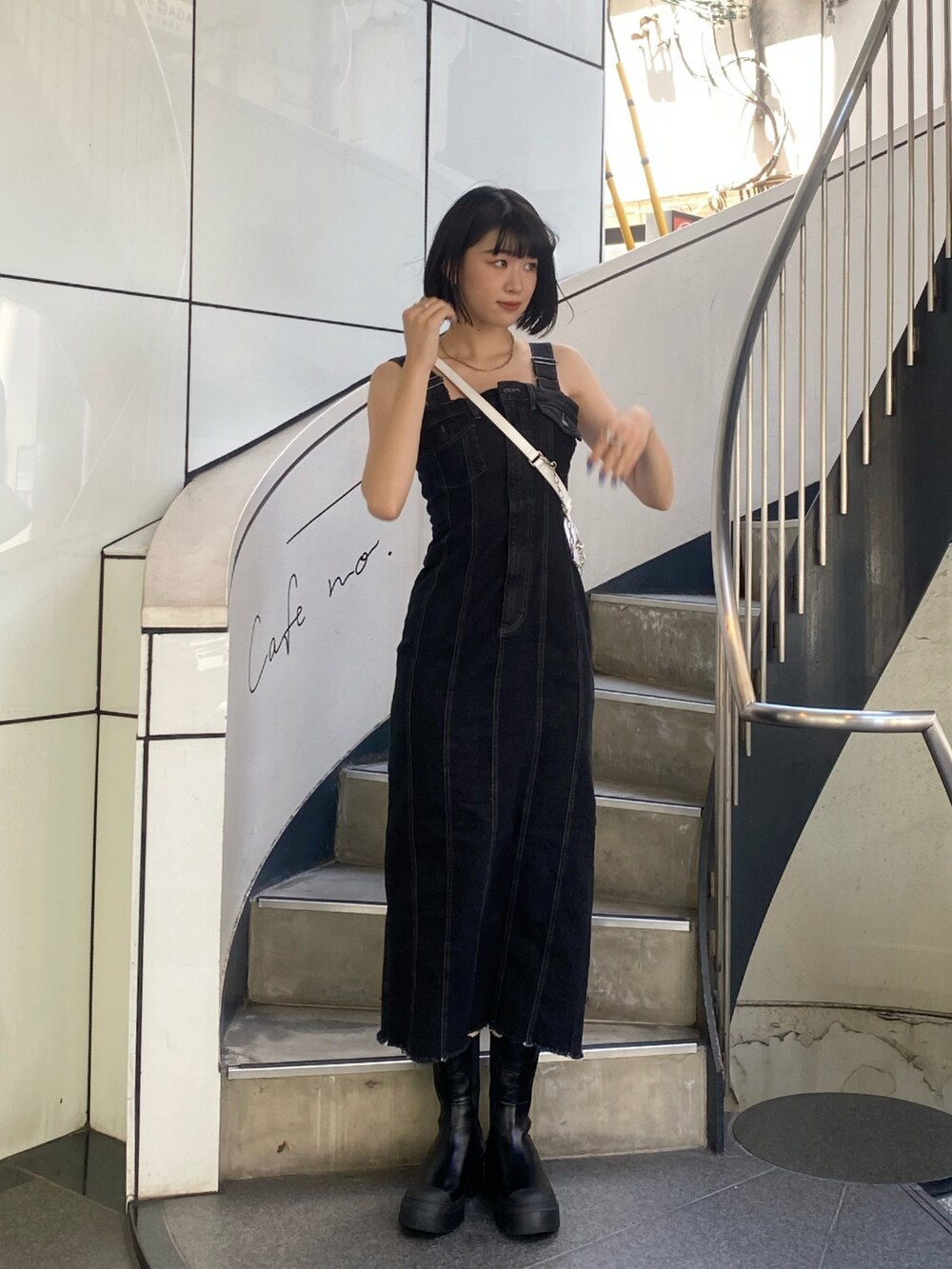 ブラック系のワンピース、ブラック系のブーツ、ホワイト系のハンドバッグを着用したレディースの夏コーディネートの2枚目の写真