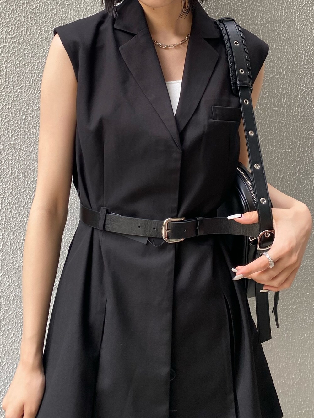 ブラック系のワンピース、ブラック系のサンダル、ブルー系のデニムパンツを着用したレディースの夏コーディネートの7枚目の写真