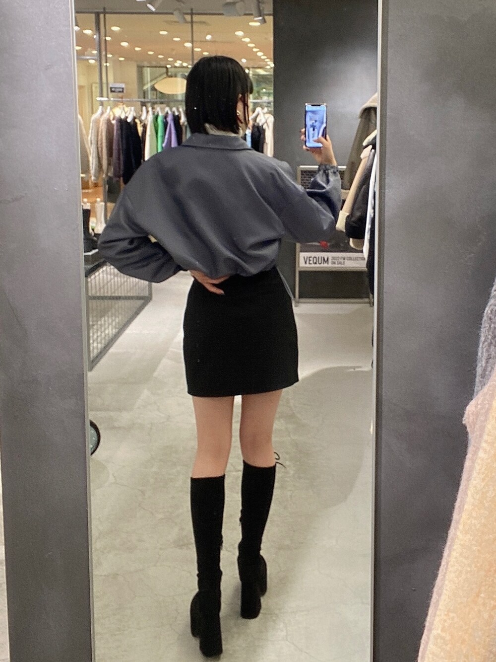 ブラック系のスカート、ブラック系のブーツ、グレー系のブルゾンを着用したレディースの冬コーディネートの3枚目の写真