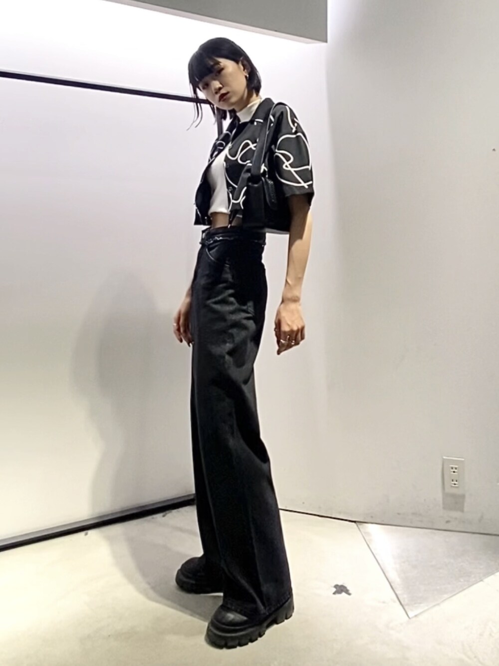 ブラック系のブーツ、ブラック系のデニムパンツ、ブラック系のショルダーバッグを着用したレディースの夏コーディネートの2枚目の写真