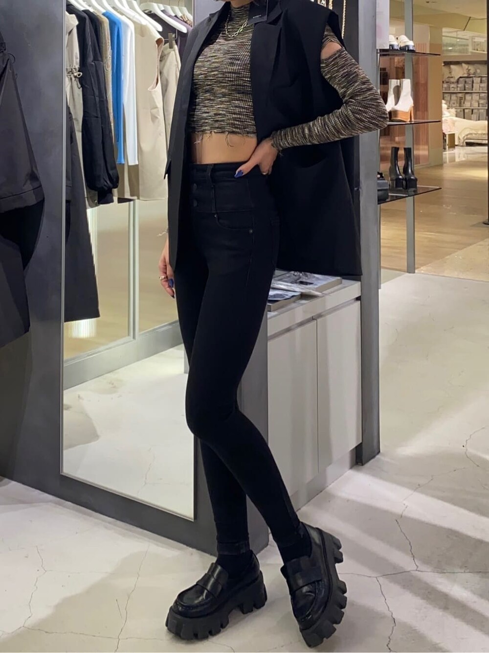 ブラック系のローファー、ブラック系のベスト、ブラック系のデニムパンツを着用したレディースの秋コーディネートの2枚目の写真