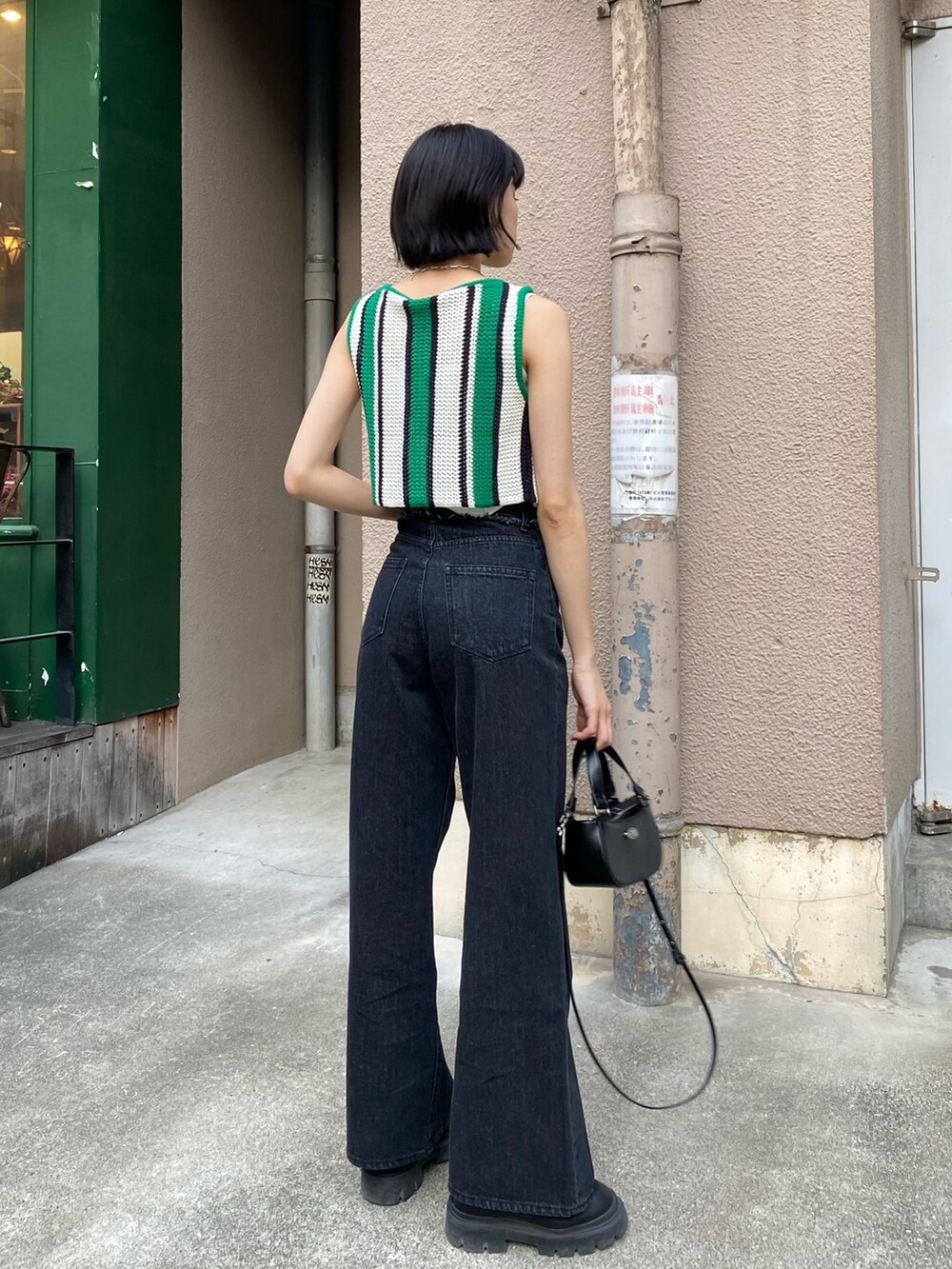 ブラック系のデニムパンツ、ブラック系のブーツ、ブラック系のハンドバッグを着用したレディースの春コーディネートの4枚目の写真