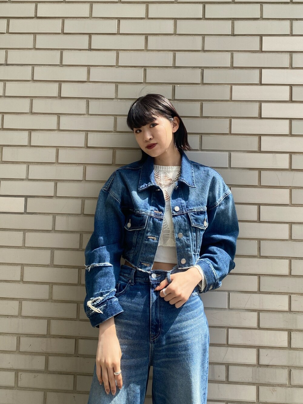 ブラック系のブーツ、ブラック系のハンドバッグ、ブルー系のデニムパンツを着用したレディースの春コーディネートの7枚目の写真