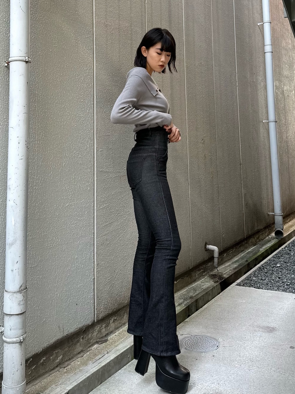 ブラック系のデニムパンツ、ブラック系のブーツ、グレー系のニット/セーターを着用したレディースの秋コーディネートの3枚目の写真