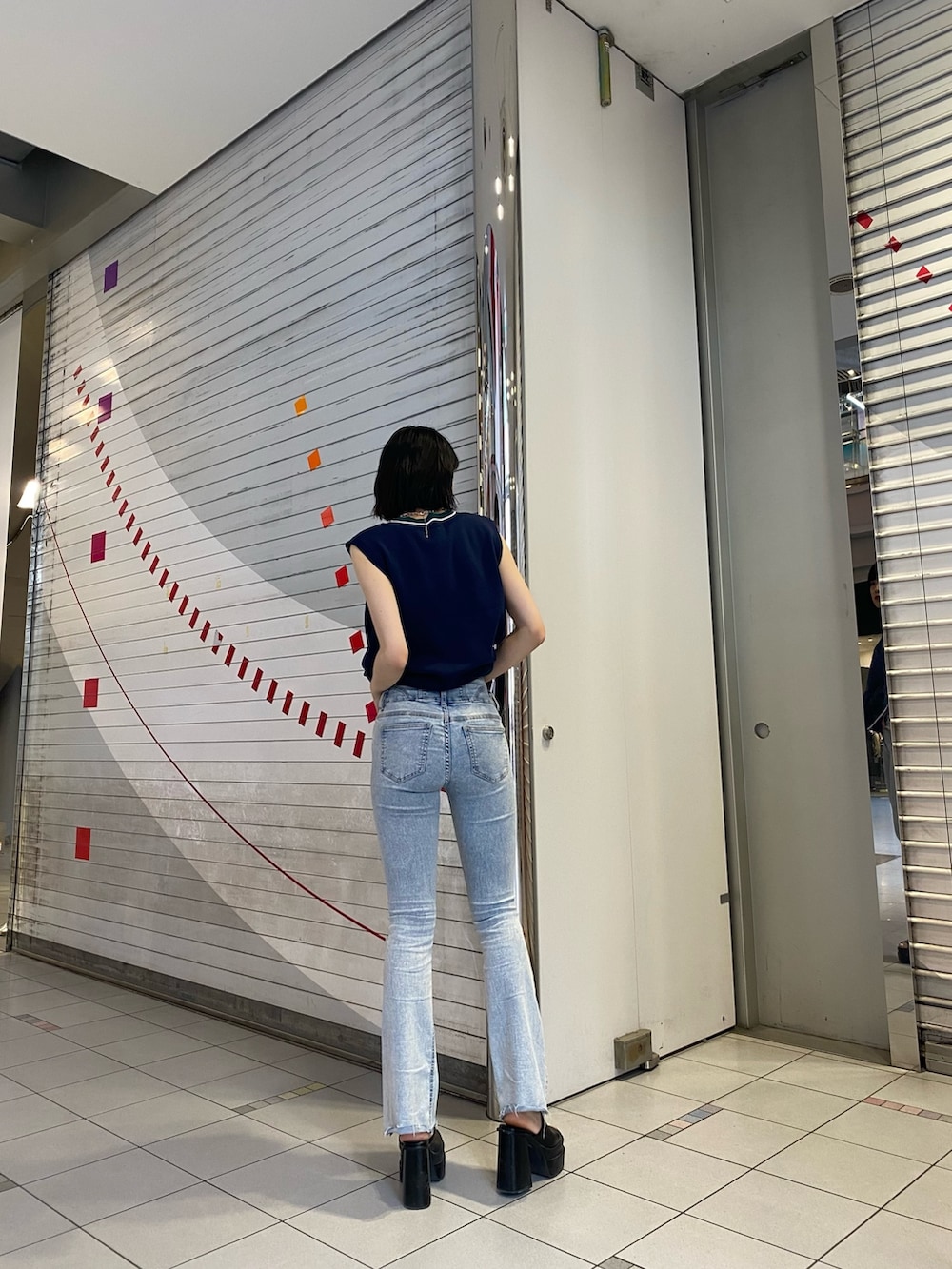 ブラック系のサンダル、ブルー系のデニムパンツ、ブルー系のベストを着用したレディースの春コーディネートの4枚目の写真