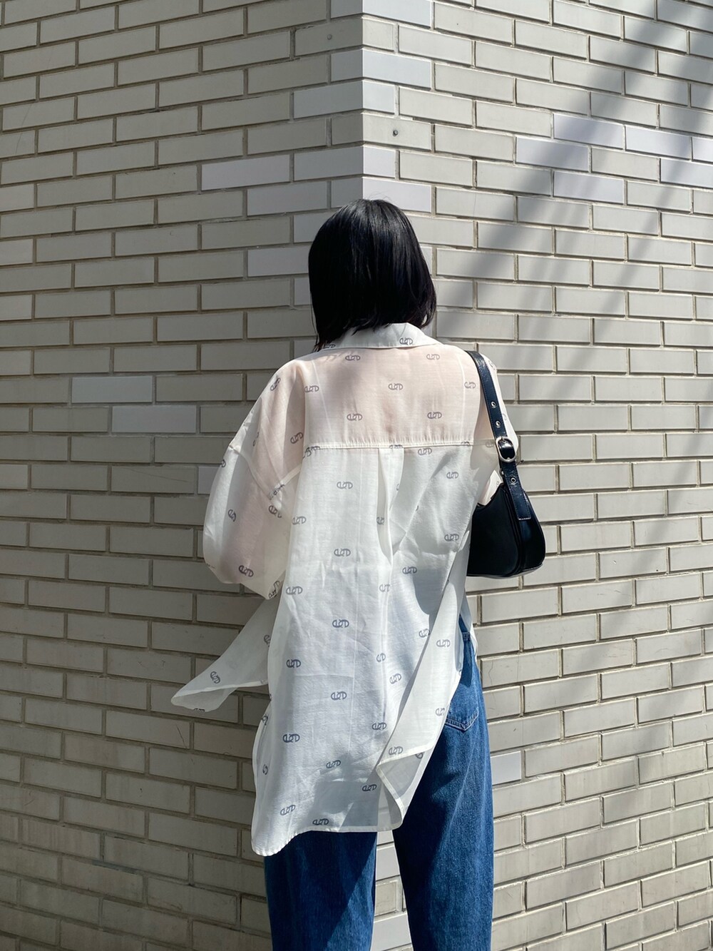 ブラック系のサンダル、ブラック系のハンドバッグ、ブルー系のデニムパンツを着用したレディースの春コーディネートの9枚目の写真