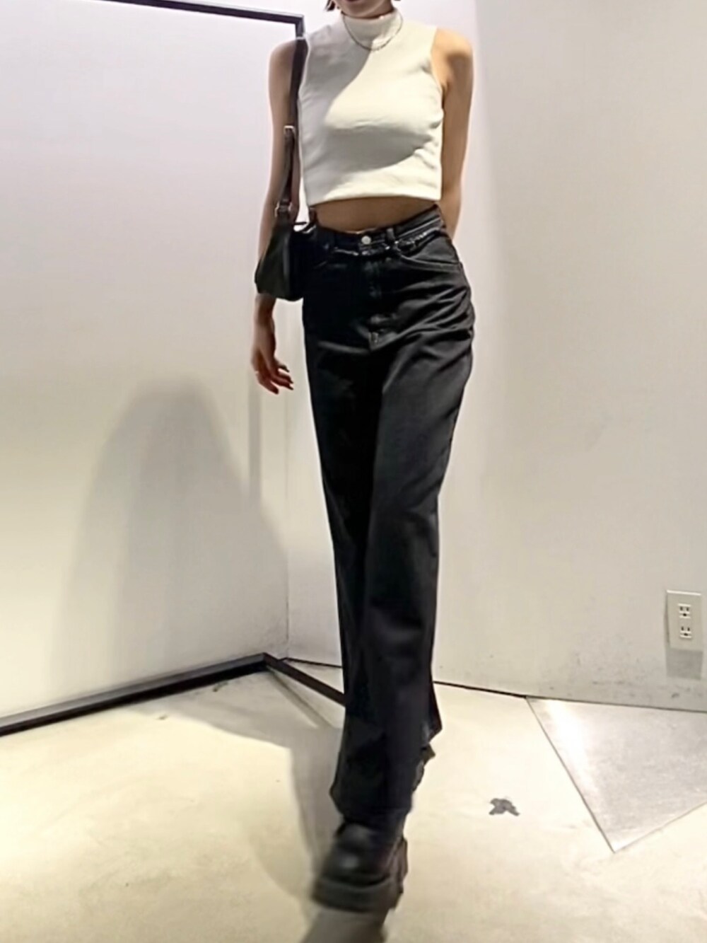 ブラック系のデニムパンツ、ブラック系のブーツ、グリーン系のハンドバッグを着用したレディースの夏コーディネートの4枚目の写真