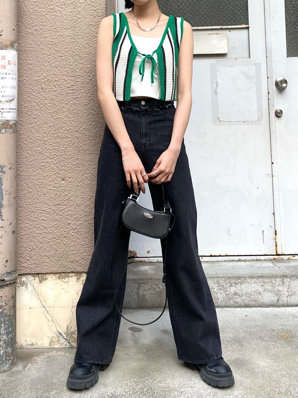 ブラック系のデニムパンツ、ブラック系のブーツ、ブラック系のハンドバッグを着用したレディースの春コーディネートの3枚目の写真