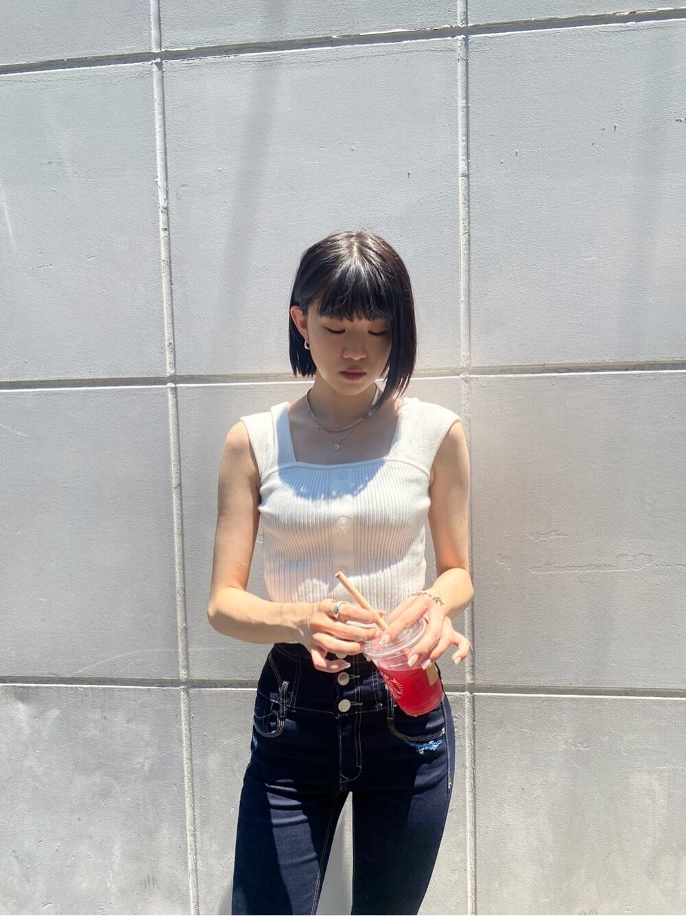 ブルー系のデニムパンツ、ホワイト系のタンクトップを着用したレディースの夏コーディネートの4枚目の写真