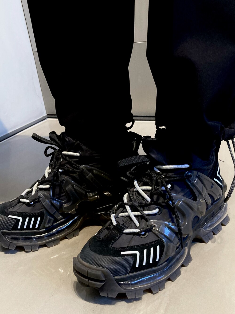 ブラック系のパーカー、ブラック系のカーゴパンツ、ブラック系のスニーカーを着用したメンズの冬コーディネートの5枚目の写真