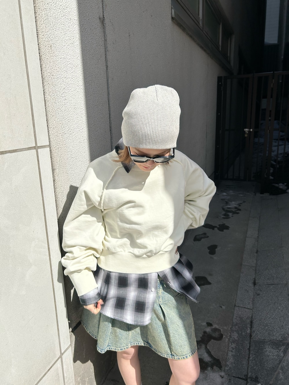 ホワイト系のスウェット、ブルー系のデニムスカート、ブラック系のシャツ/ブラウスを着用したレディースの春コーディネートの3枚目の写真