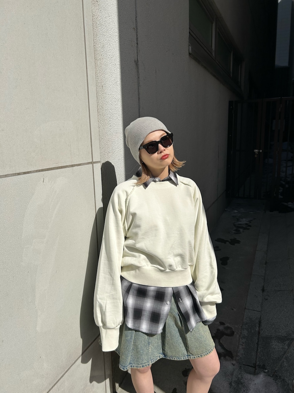 ホワイト系のスウェット、ブルー系のデニムスカート、ブラック系のシャツ/ブラウスを着用したレディースの春コーディネートの2枚目の写真