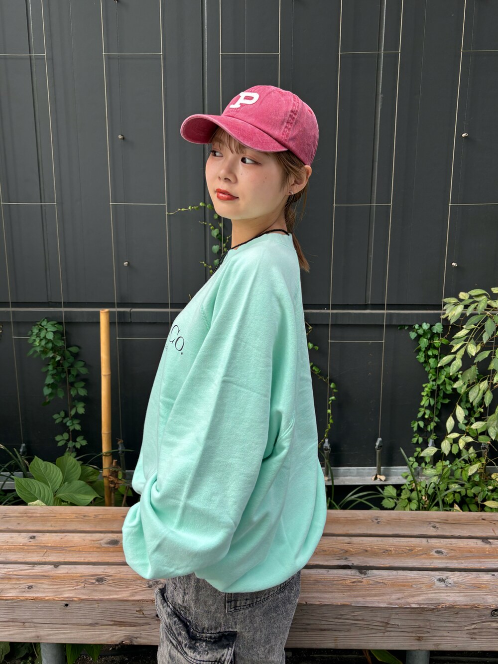 ブラック系のデニムパンツ、グリーン系のTシャツ/カットソー、ブラック系のネックレスを着用したレディースの秋コーディネートの2枚目の写真