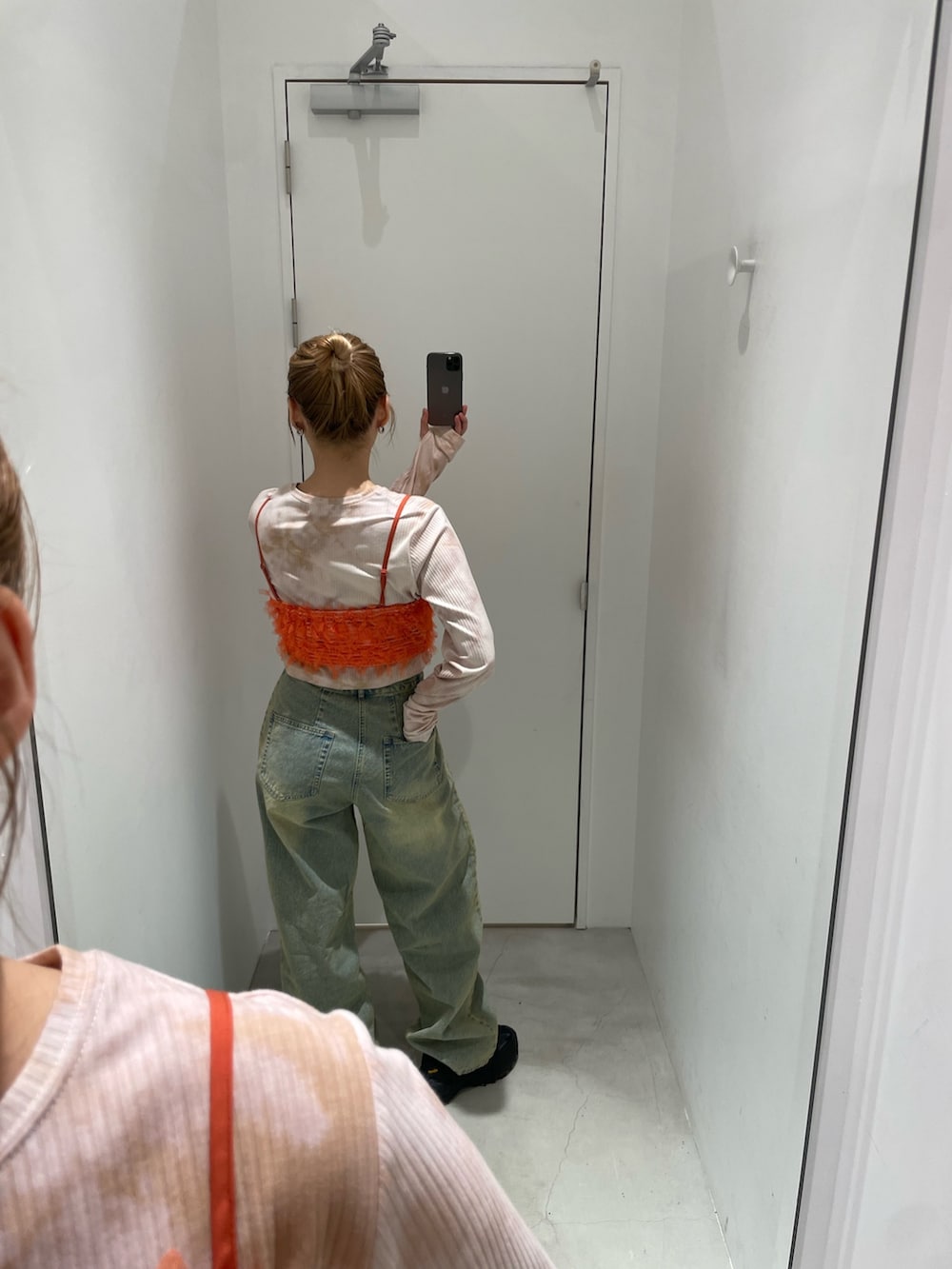 ブルー系のデニムパンツ、オレンジ系のキャミソール、ベージュ系のTシャツ/カットソーを着用したレディースの春コーディネートの2枚目の写真