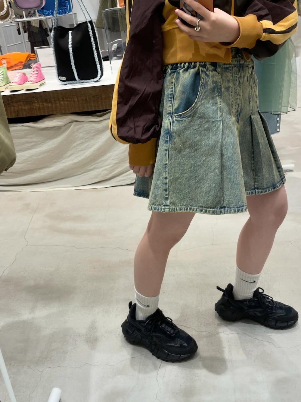 ブルー系のデニムスカート、ブラウン系のナイロンジャケット、ブラック系のTシャツ/カットソーを着用したレディースの冬コーディネートの2枚目の写真