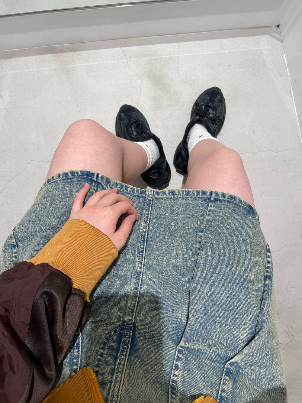 ブルー系のデニムスカート、ブラウン系のナイロンジャケット、ブラック系のTシャツ/カットソーを着用したレディースの冬コーディネートの5枚目の写真