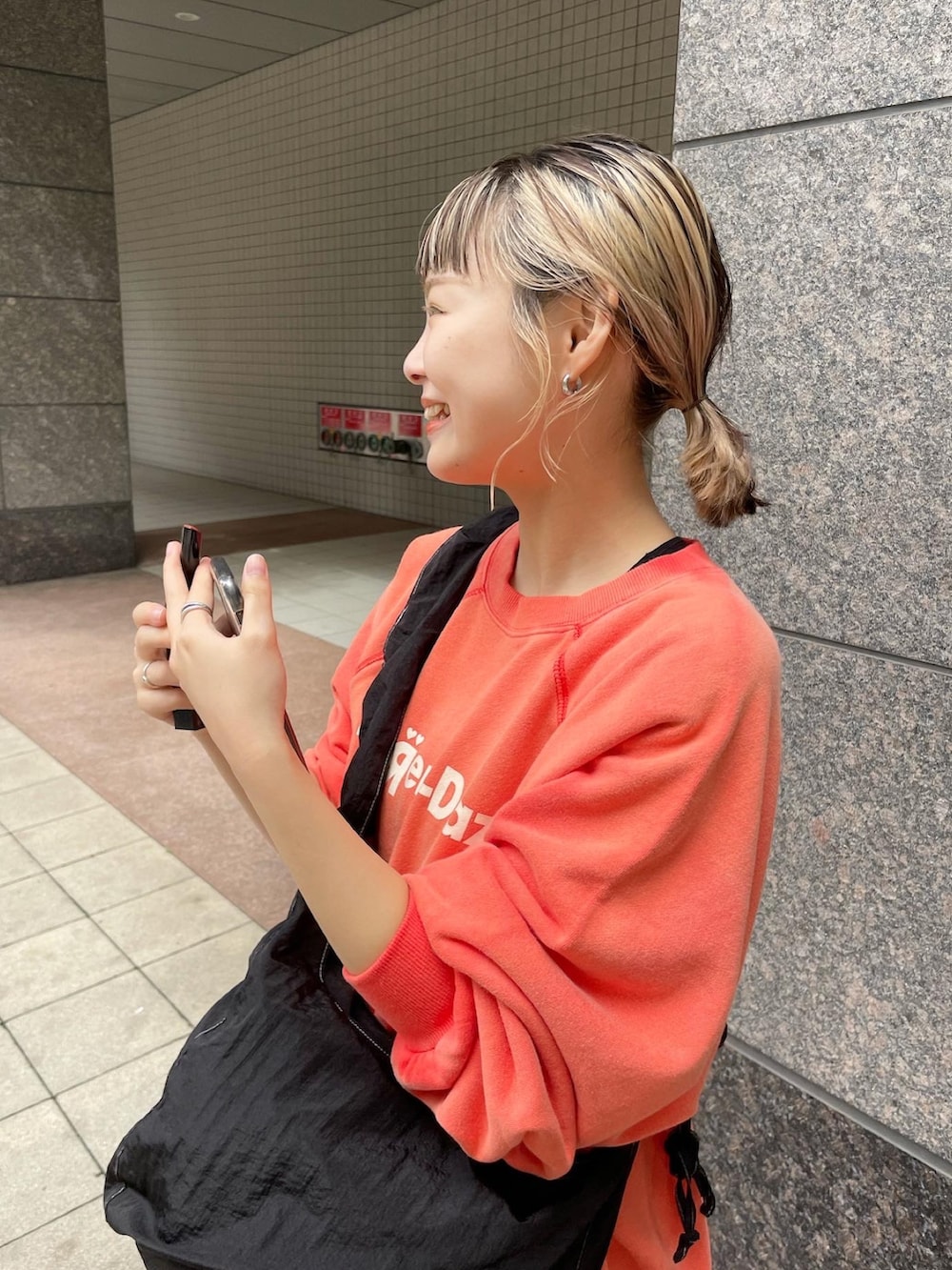 レッド系のスウェット、ブラック系のデニムスカート、ブラック系のショルダーバッグを着用したレディースの秋コーディネートの3枚目の写真