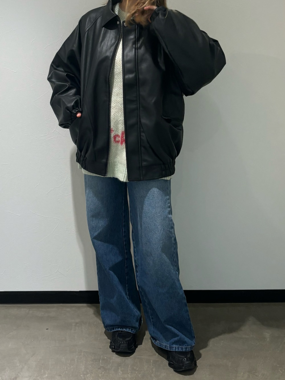 ブラック系のブルゾン、グリーン系のニット/セーター、ブルー系のデニムパンツを着用したレディースの秋コーディネートの2枚目の写真