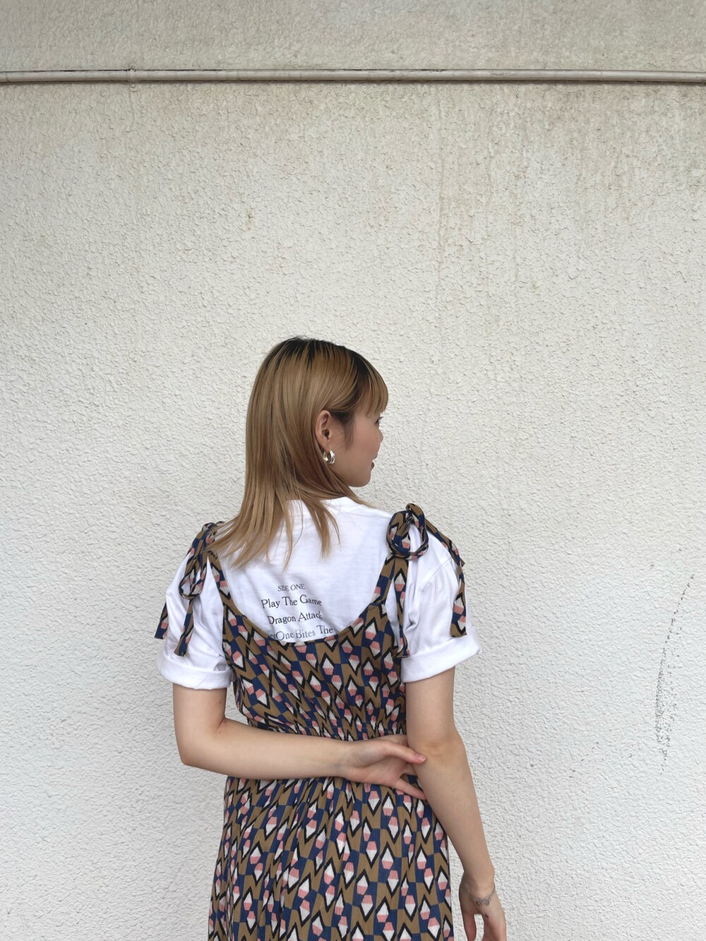 ベージュ系のワンピース、ホワイト系のTシャツ/カットソー、ブラック系のサンダルを着用したレディースの夏コーディネートの3枚目の写真