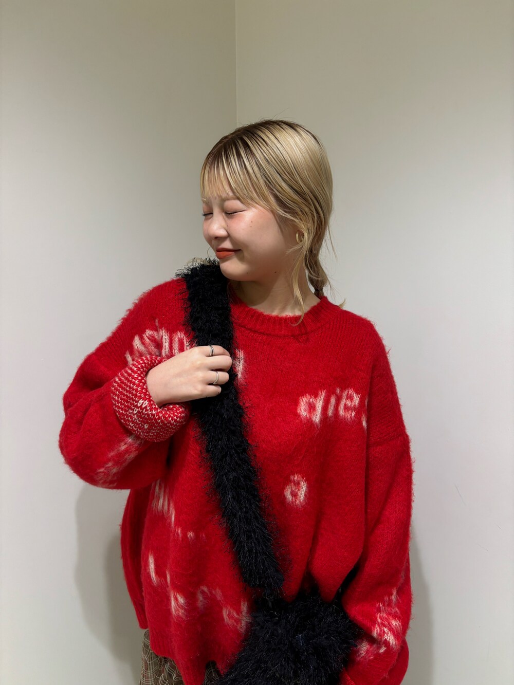 レッド系のニット/セーター、ブラック系のショルダーバッグ、ブラウン系のスカートを着用したレディースの冬コーディネートの3枚目の写真