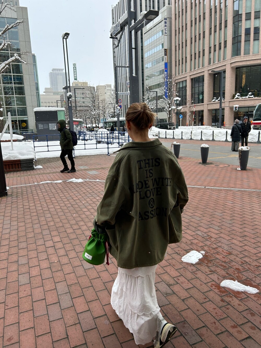 ホワイト系のスカート、グリーン系のカバーオール、グリーン系のハンドバッグを着用したレディースの冬コーディネートの4枚目の写真