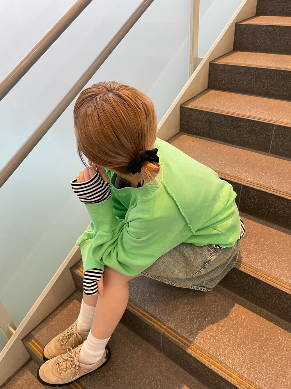 グリーン系のスウェット、ブラック系のTシャツ/カットソー、ブルー系のデニムスカートを着用したレディースの春コーディネートの4枚目の写真