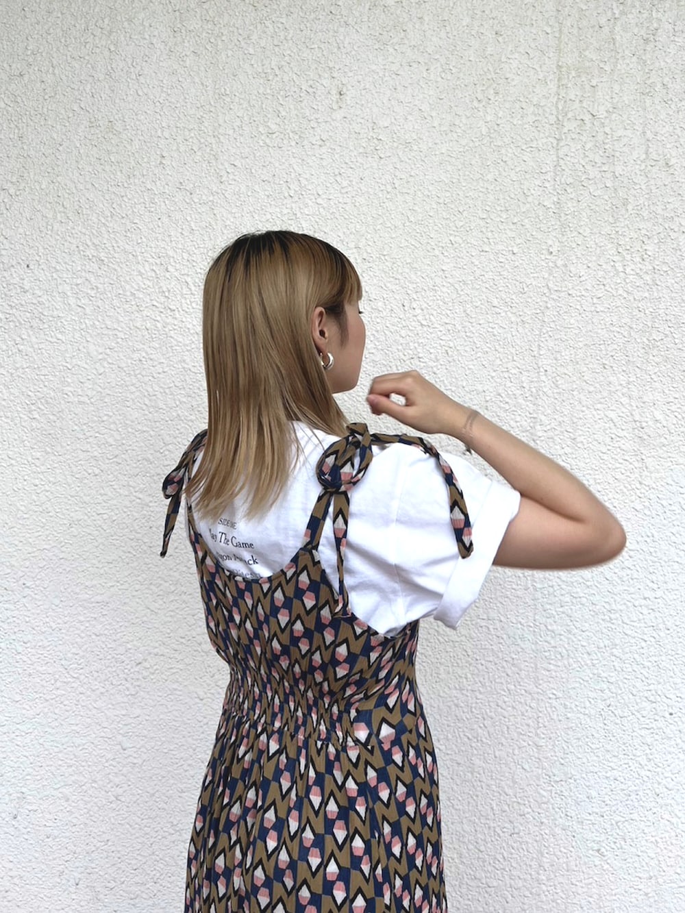 ベージュ系のワンピース、ホワイト系のTシャツ/カットソー、ブラック系のサンダルを着用したレディースの夏コーディネートの2枚目の写真