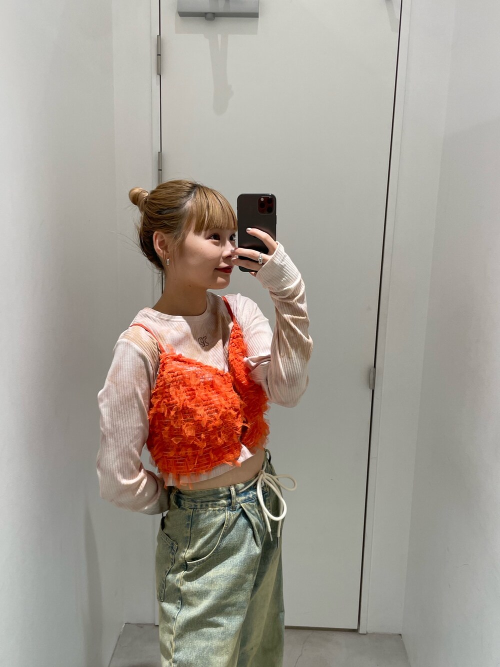 ブルー系のデニムパンツ、オレンジ系のキャミソール、ベージュ系のTシャツ/カットソーを着用したレディースの春コーディネートの4枚目の写真