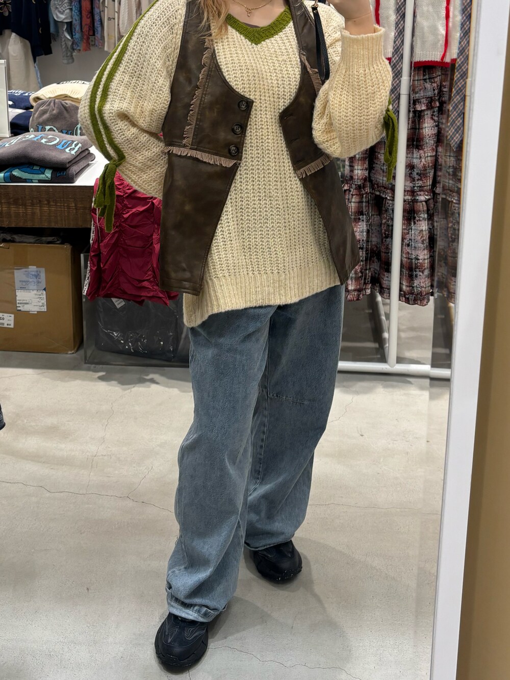 ブラウン系のベスト、ブルー系のデニムパンツ、ベージュ系のニット/セーターを着用したレディースの冬コーディネートの2枚目の写真
