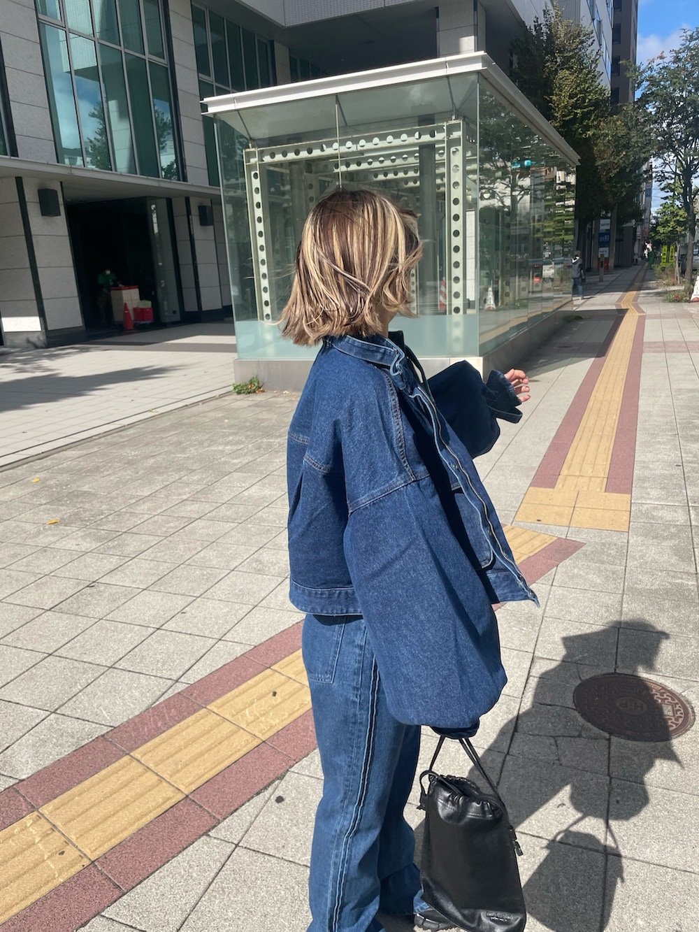 ブルー系のデニムパンツ、ブルー系のデニムジャケット、ブラウン系のTシャツ/カットソーを着用したレディースの秋コーディネートの3枚目の写真