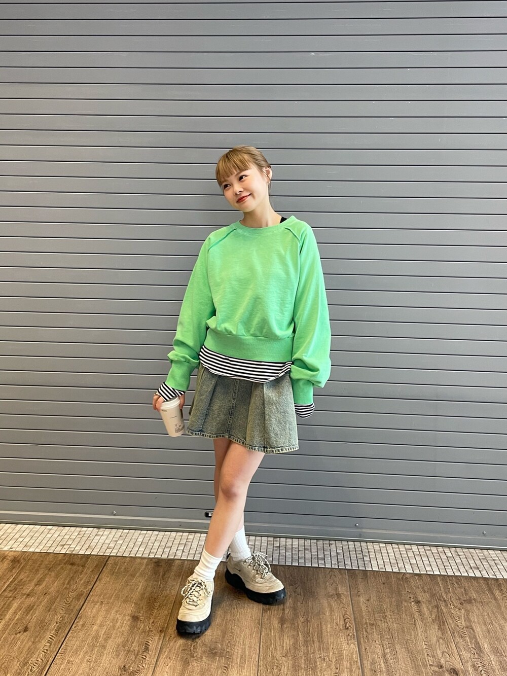 グリーン系のスウェット、ブラック系のTシャツ/カットソー、ブルー系のデニムスカートを着用したレディースの春コーディネートの3枚目の写真