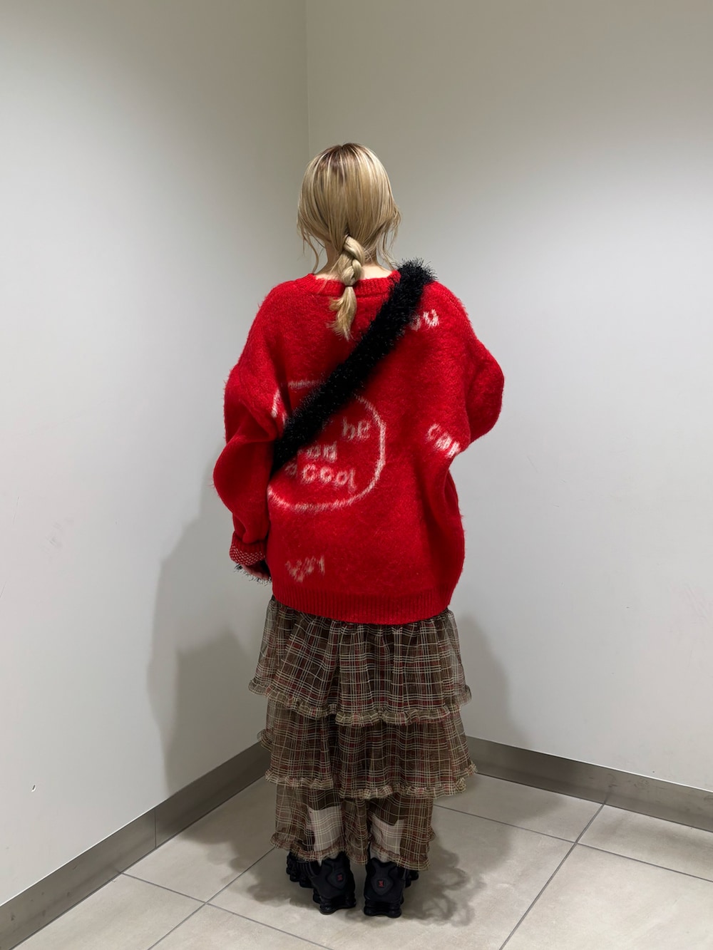 レッド系のニット/セーター、ブラック系のショルダーバッグ、ブラウン系のスカートを着用したレディースの冬コーディネートの2枚目の写真