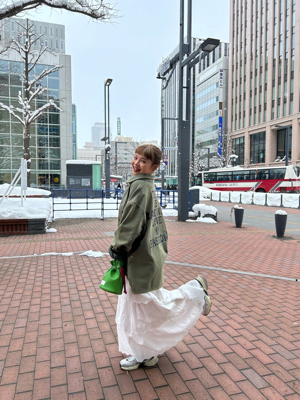 ホワイト系のスカート、グリーン系のカバーオール、グリーン系のハンドバッグを着用したレディースの冬コーディネートの3枚目の写真