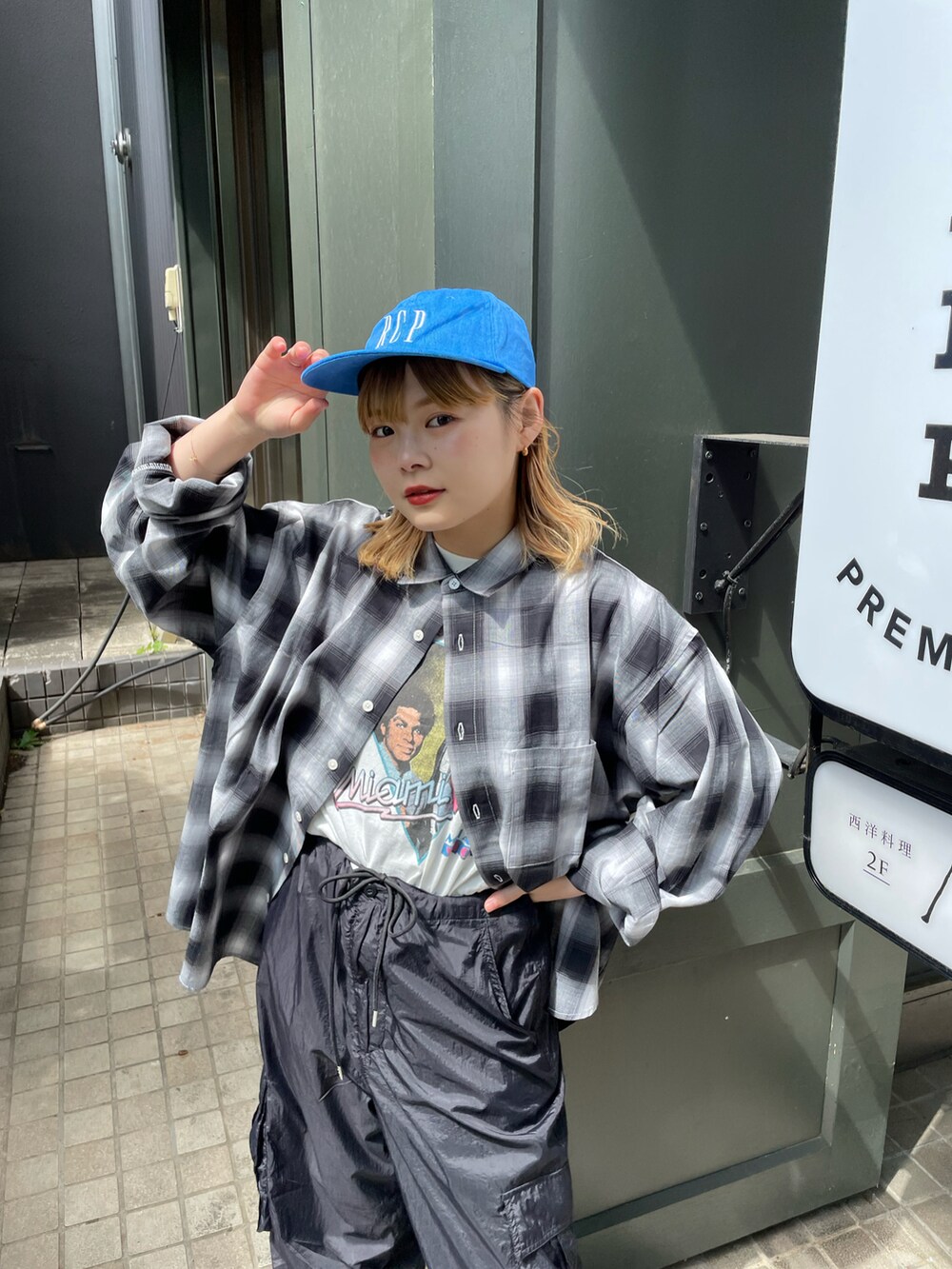 ブラック系のカーゴパンツ、ブラック系のシャツ/ブラウス、ブルー系のキャップを着用したレディースの春コーディネートの2枚目の写真