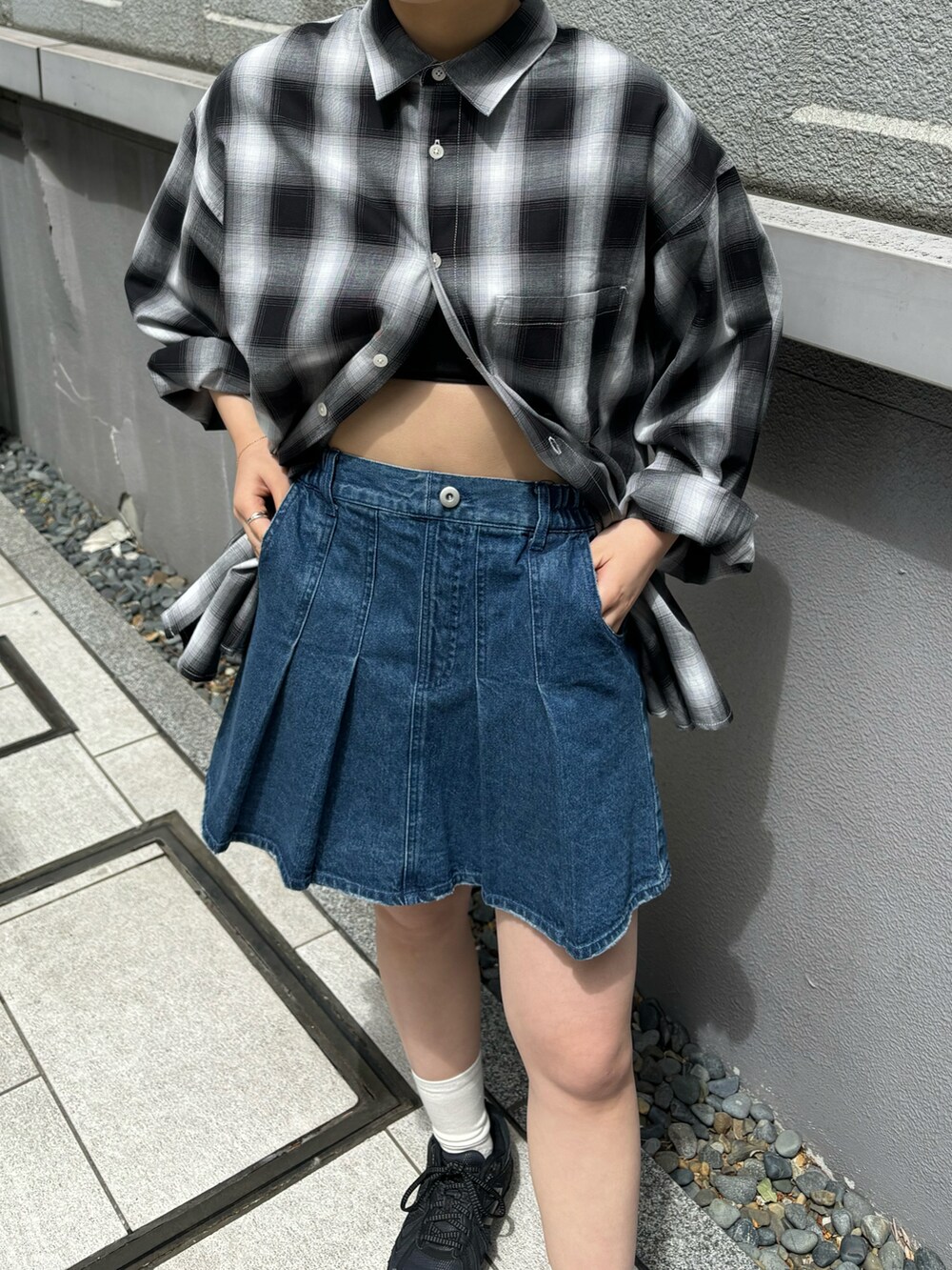 ブルー系のデニムスカート、ブラック系のシャツ/ブラウスを着用したレディースの春コーディネートの2枚目の写真