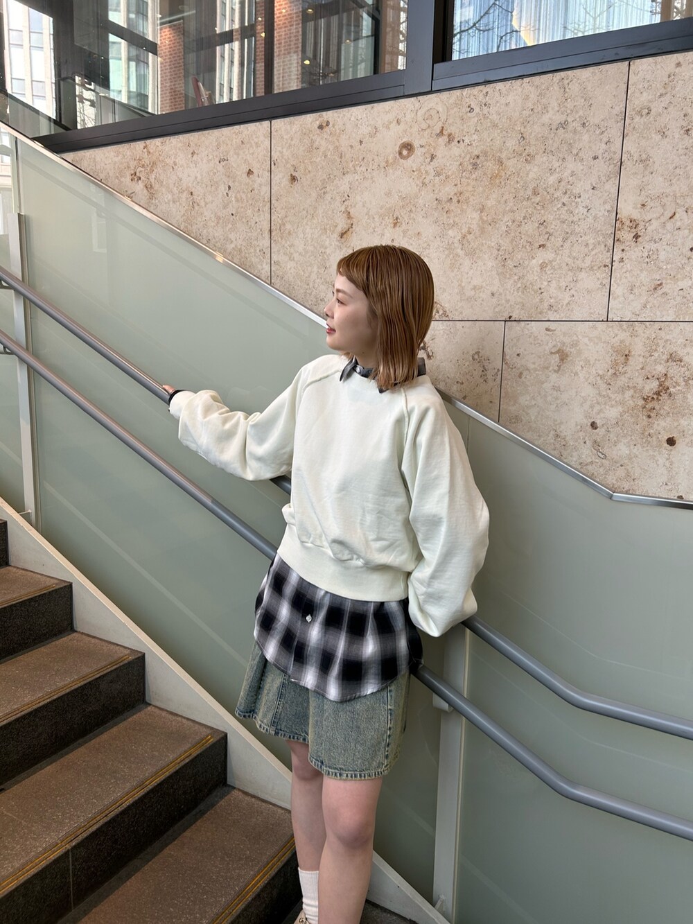 ホワイト系のスウェット、ブルー系のデニムスカート、ブラック系のシャツ/ブラウスを着用したレディースの春コーディネートの4枚目の写真