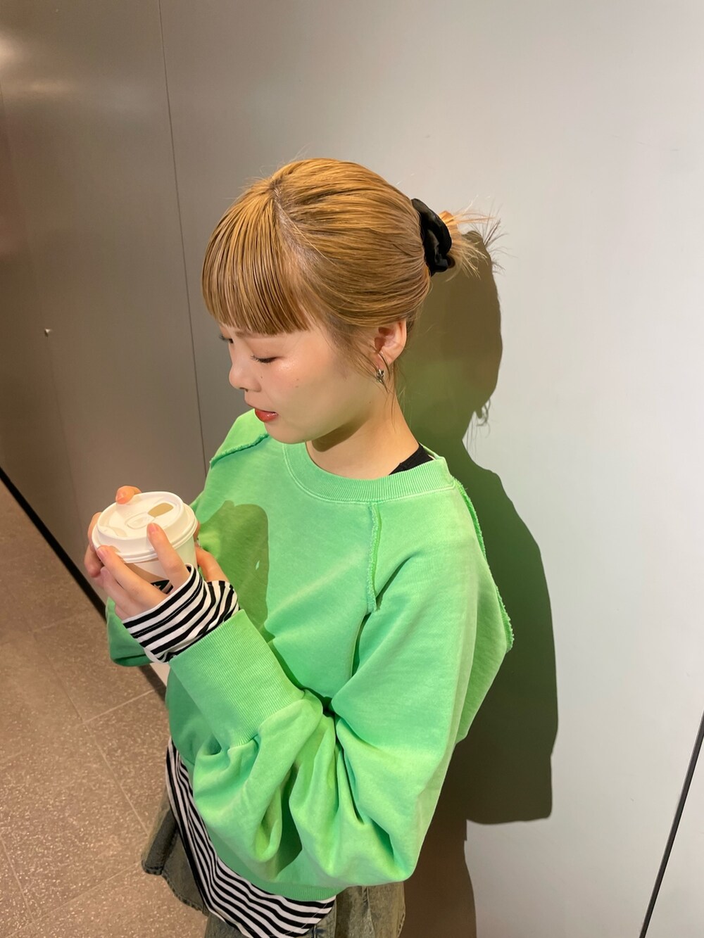 グリーン系のスウェット、ブラック系のTシャツ/カットソー、ブルー系のデニムスカートを着用したレディースの春コーディネートの2枚目の写真