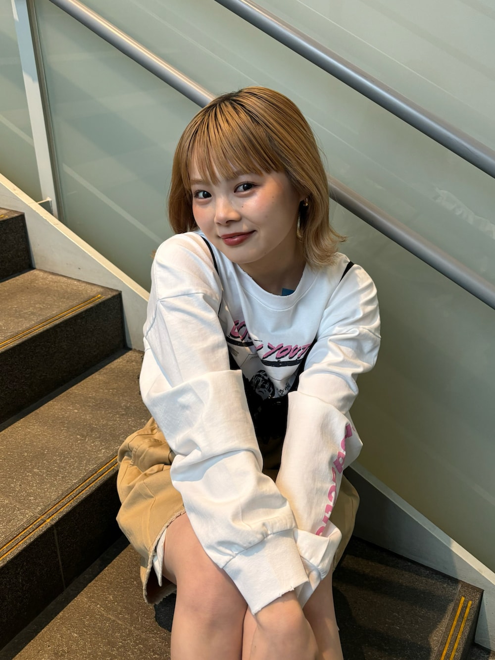 ベージュ系のスカート、オレンジ系のキャミソール、ホワイト系のTシャツ/カットソーを着用したレディースの春コーディネートの3枚目の写真