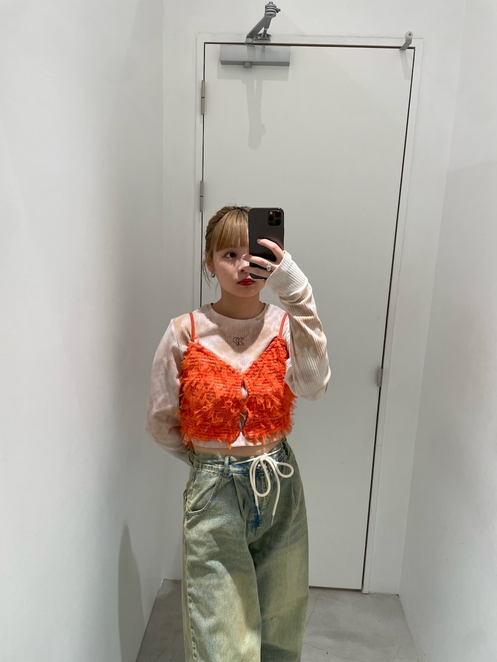 ブルー系のデニムパンツ、オレンジ系のキャミソール、ベージュ系のTシャツ/カットソーを着用したレディースの春コーディネートの3枚目の写真